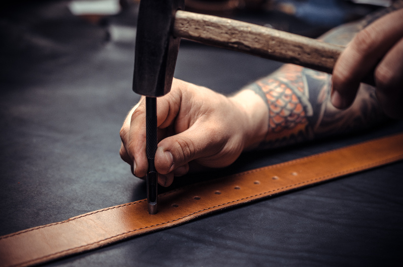 Wizard leather punches holes in the men's belt.